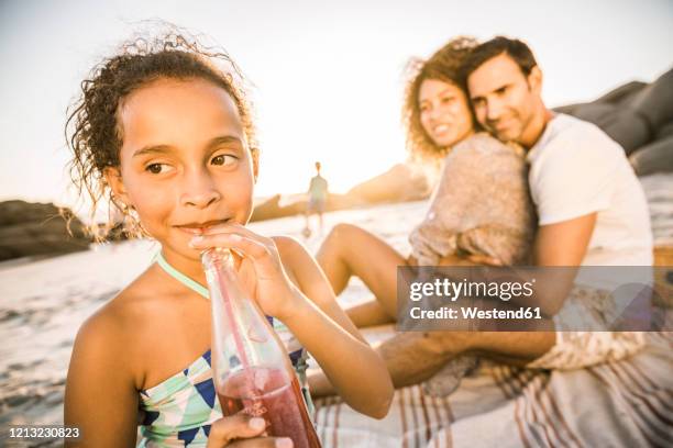 girl with her family having a soft drink at sunset at the beach - couple portrait soft ストックフォトと画像