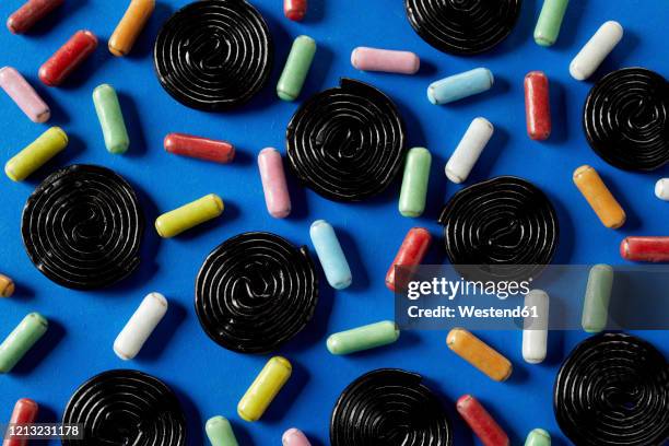 spiral wheels of licorice candy with sugar coated licorice on blue background - licorice stock pictures, royalty-free photos & images