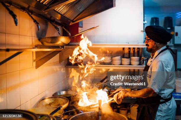 indian chef flambing food in restaurant kitchen - indian chef stock pictures, royalty-free photos & images