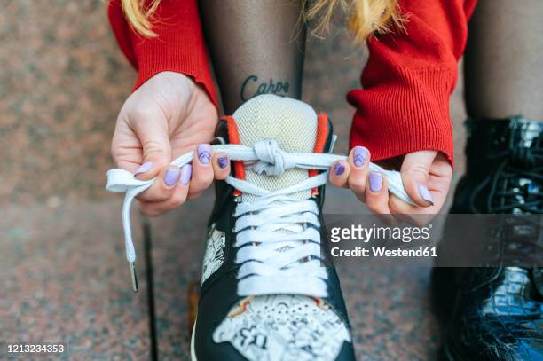 close-up of young woman putting on roller skates - senkel stock-fotos und bilder