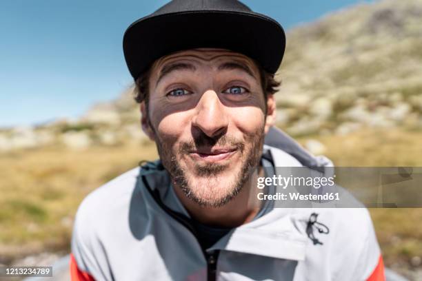 portrait of smiling young man looking at camera, sitting in rowing boat - grimassen stock-fotos und bilder