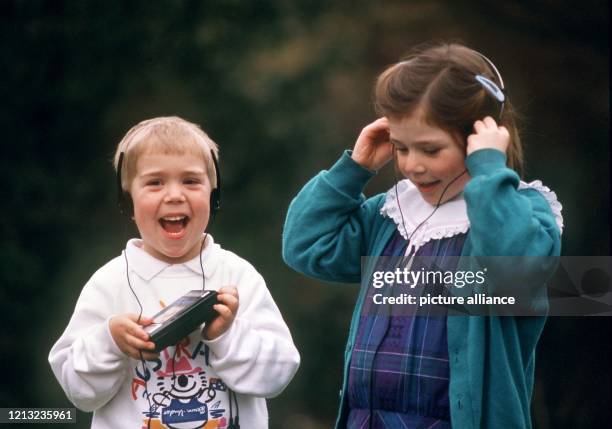 Vergnügt hören diese beiden Kinder zusammen Musik mit einem Walkman. .