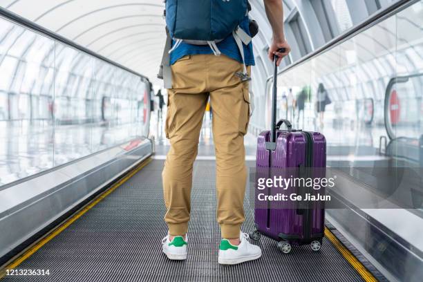 a traveler walking on moving walkway in the airport - emigration and immigration foto e immagini stock