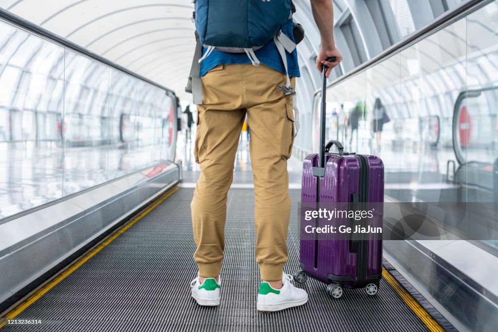 A Traveler walking on moving walkway in the airport