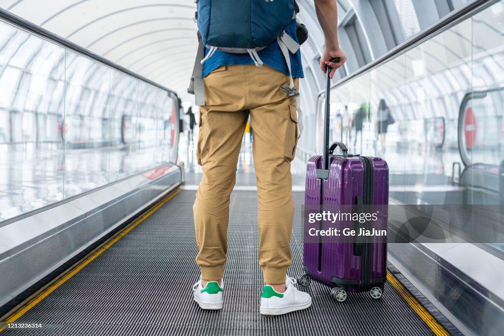 A Traveler walking on moving walkway in the airport
