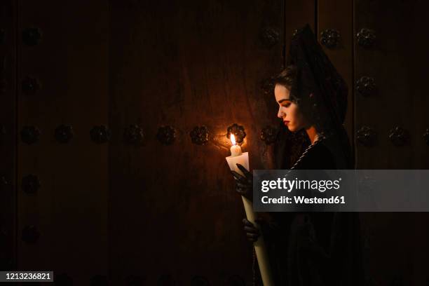 beautiful woman made up in traditional costume for la semana santa, holding burning candle - velo fotografías e imágenes de stock