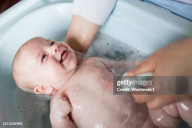 mother bathing her baby boy in a tub - bathing stock pictures, royalty-free photos & images