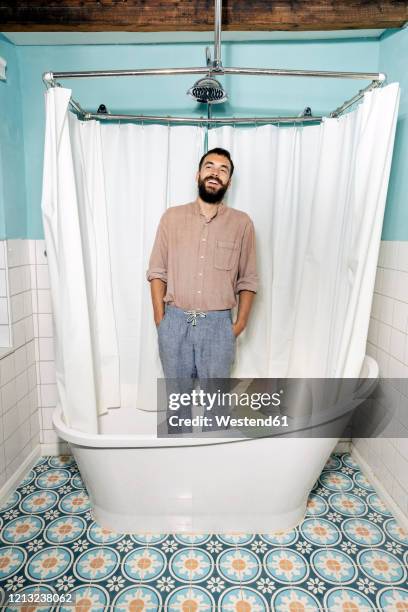 young man standing in bath tub, laughing - bath shower stock pictures, royalty-free photos & images