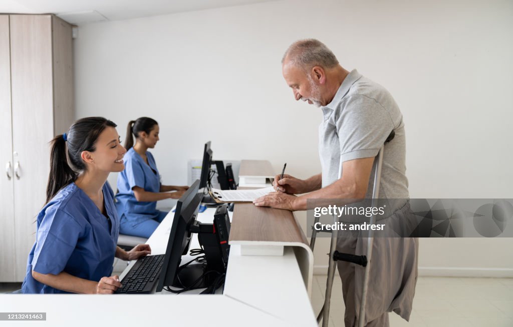 Friendly receptionist helping disabled man filling forms at the hospital