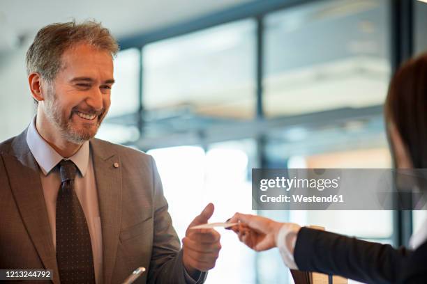 portrait of smiling businessman checking in at hotel reception - カードキー ストックフォトと画像