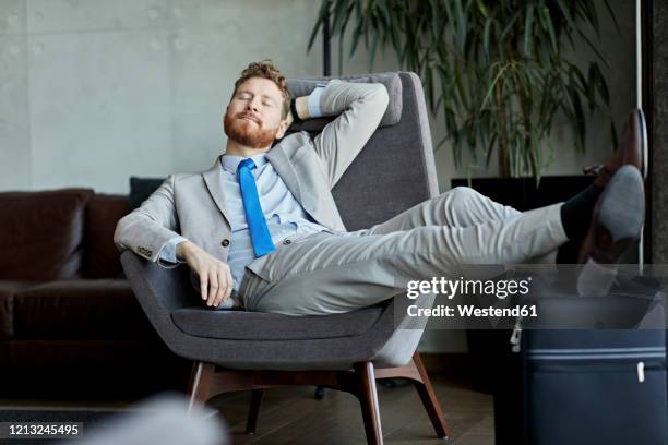 businessman napping in hotel lobby - wheeled luggage stock-fotos und bilder