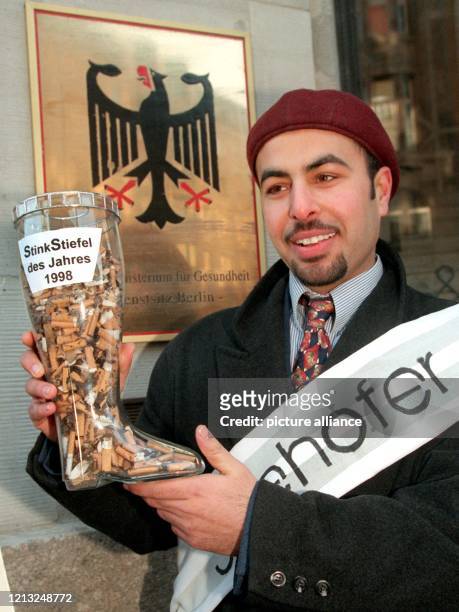 Den mit Zigarettenkippen gefüllten "Stinkstiefel des Jahres" hält Emawi Ashief vom Nichtraucherbund e.V. Am 2.2.1998 vor der Außenstelle des...