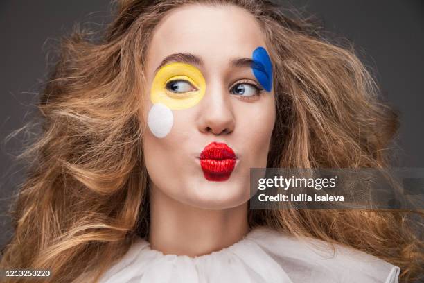 happy young woman with painted face in clown costume sending air kiss - clown face paint stock pictures, royalty-free photos & images