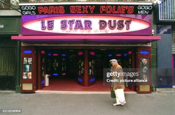 Eine alte Frau geht im März 1997, mit Einkaufstüten bepackt, an einem Striptease-Lokal auf dem Pariser Boulevard de Clichy vorbei.