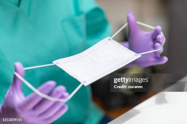 handen in beschermende handschoenen die beschermend masker houden - face mask protective workwear stockfoto's en -beelden