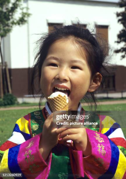 Lächelnd schleckt ein kleines asiatisches Mädchen eine Eistüte, aufgenommen am . Foto: Werner Baum +++ dpa - Report+++