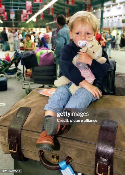 Urlaubsreif? Der dreijährige Julian sitzt am 27.6.1998 im Abflugbereich des Düsseldorfer Flughafens auf gepackten Koffern. Seine Plüschkuh fest im...