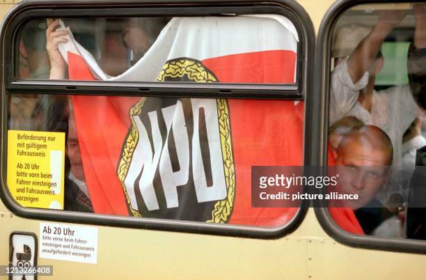 Hinter der Fensterscheibe eines Doppeldecker-Busses befestigen NPD-Anhänger am 20.6.1998 am Rande einer Kundgebung der rechtsextremen Partei in...