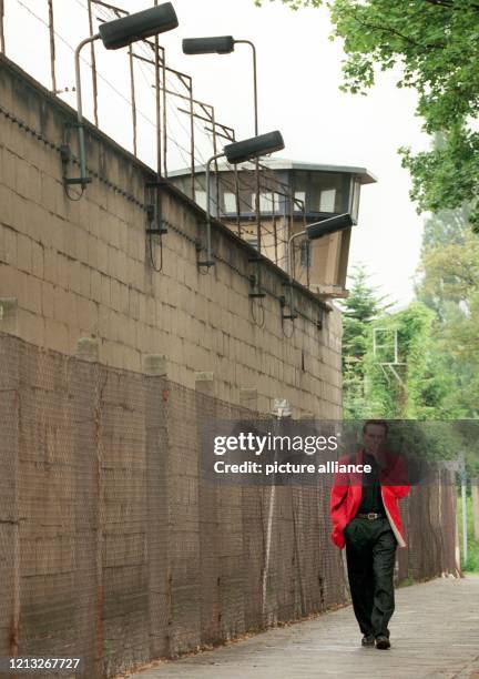 Ein Mann geht am 16.6.1998 an einer fünf Meter hohen durch Stacheldraht und Wachturm gesicherten Mauer vorbei, die zu der ehemaligen Haft- und...