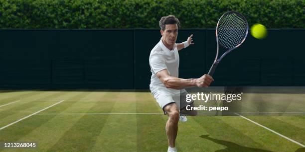 männlicher tennisspieler über volley während spiel auf gras - grass court stock-fotos und bilder