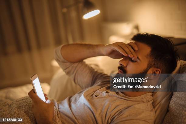 ongerust gemaakte jonge mens die slecht nieuws op slimme telefoon leest - man shock stockfoto's en -beelden