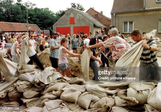 Mit vereinten Kräften stapeln die Dorfbewohner von Altreetz im Oderbruch am 29.7.1997 Sandsäcke vor ihren Häusern, um diese vor der möglichen...