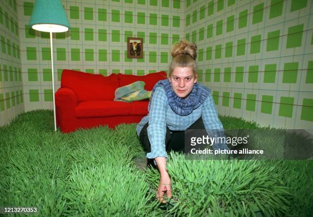 Eine junge Dame in einer Graslandschaft vor einer roten Stoffcouch, mit der eine skandinavische Firma auf der Heimtextil in Frankfurt Werbung für...