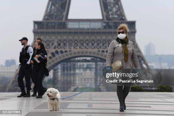 Woman wears protective gloves near the Eiffel tower the second day after the announcement by French President Emmanuel Macron of the confinement of...