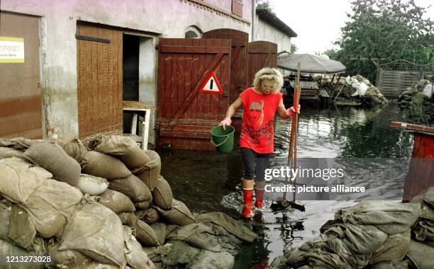 Mit Eimer und Besen in den Händen läuft Marianne Schaar am 6.8.1997 durch den noch unter Wasser stehenden Hof ihres Hauses in Wiesenau südlich von...