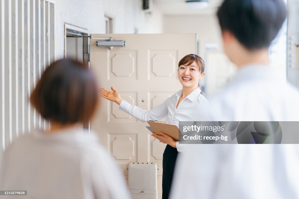 Female real estate agent guiding young couple to new house