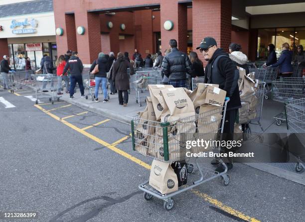 Worker leaves Whole Foods with Amazon Prime delivery packages on March 18, 2020 in Jericho, New York. The World Health Organization declared COVID-19...