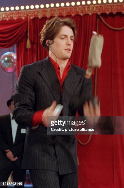 Der Schauspieler Hugh Grant jongliert am 8.12.1996 während der ZDF-Show "Wetten, daß..." mit drei verschiedenen Gegenständen, um seine verlorene...
