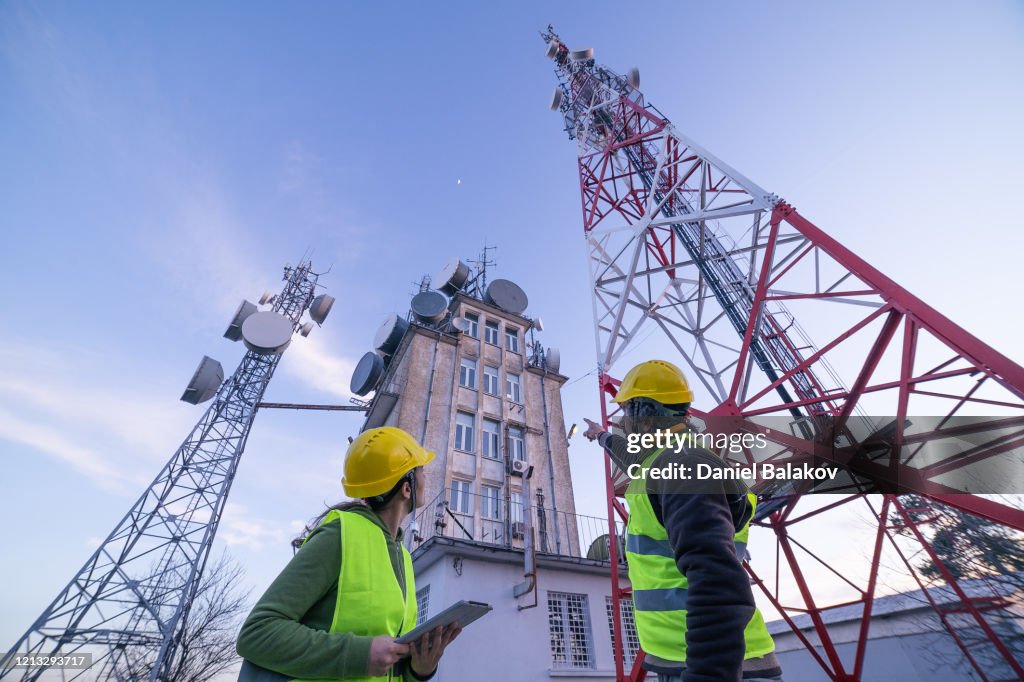 Ingenieros trabajando en el campo cerca de una torre de telecomunicaciones. Trabajo en Equipo.