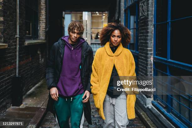 pareja joven caminando por la calle - alla moda fotografías e imágenes de stock