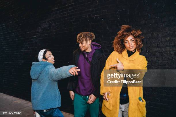three friends dancing in the city against a black brick wall - rapper stock pictures, royalty-free photos & images
