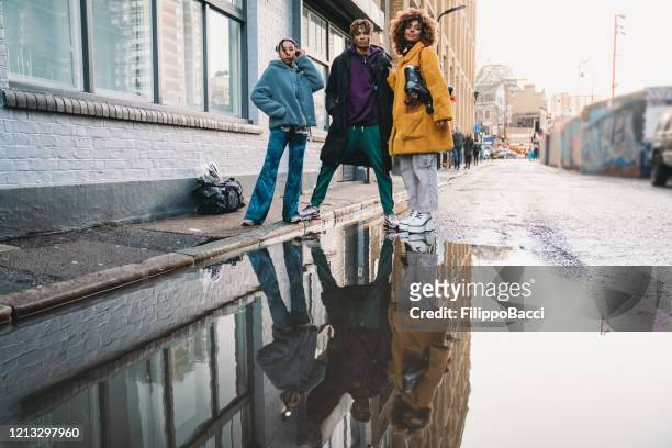 three hip friends reflected in a puddle in the city - rapper stock pictures, royalty-free photos & images