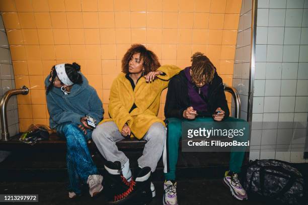 drei freunde warten in einer u-bahn-station auf den zug - station stock-fotos und bilder