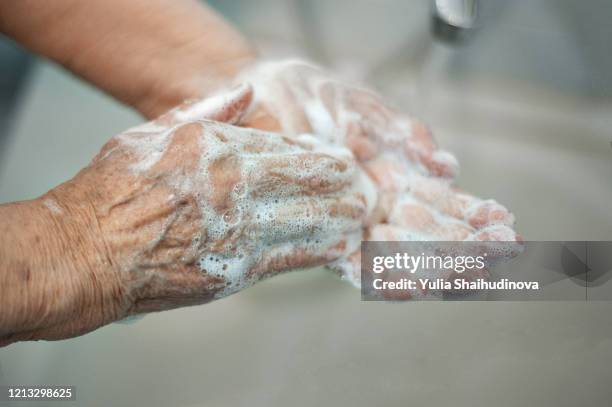 coronavirus covid-19 old woman is washing her hands with soap - infectious disease fotografías e imágenes de stock