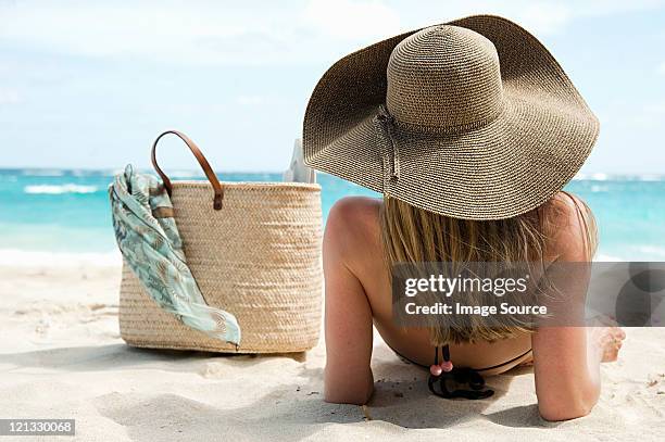 woman lying on sandy beach, mustique, grenadine islands - cappello per il sole foto e immagini stock
