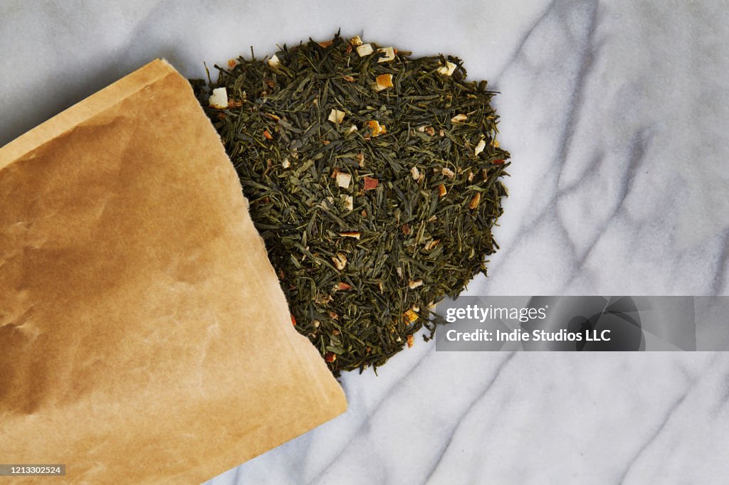 Directly Above photo of Loose Tea Spilling out of Brown Paper Bag Over Marble Stone Background