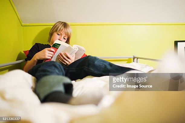 boy reading book on bed - 10 11 jaar stockfoto's en -beelden