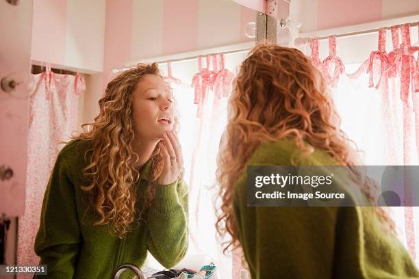 teenage girl checking skin in bathroom mirror - beauty mirror stock pictures, royalty-free photos & images