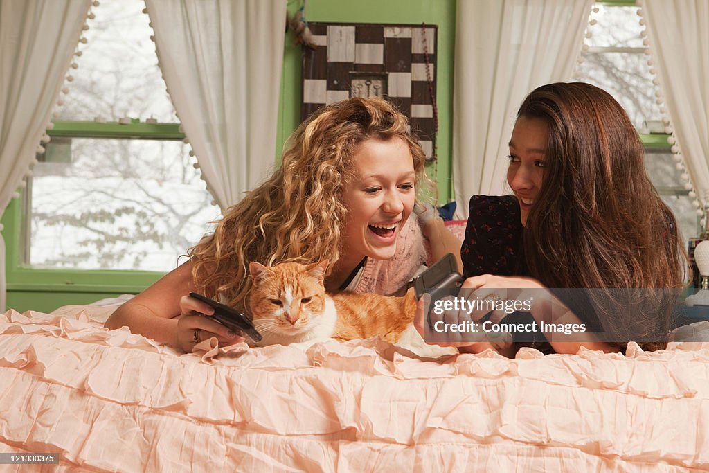 Teenage girls yacer en la cama con teléfono inteligente