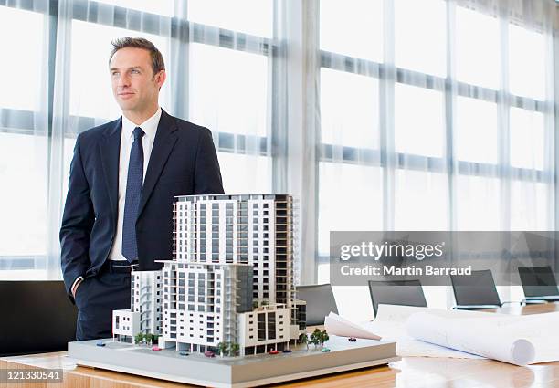 businessman standing in conference room with model building - architectural model stock pictures, royalty-free photos & images