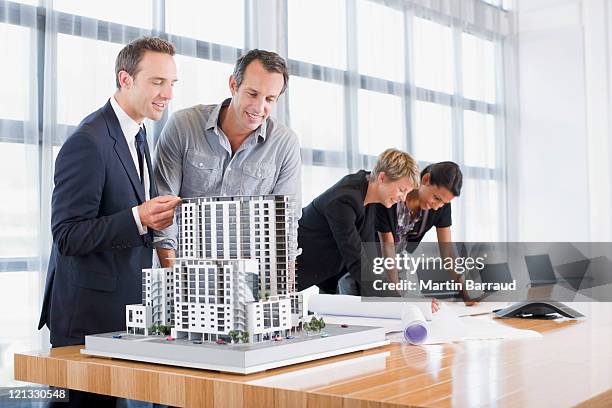 business people looking at blueprints and model building - architectural model stockfoto's en -beelden