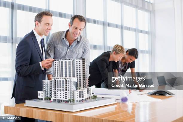 business people looking at blueprints and model building - office small business stock pictures, royalty-free photos & images