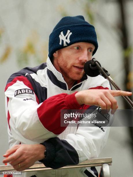 Mit einer Pudelmütze auf dem Kopf gibt Boris Becker vom Schiedsrichtersitz aus Anweisungen an die Teilnehmer einer Kinder-Tennistrainingsstunde. Auf...