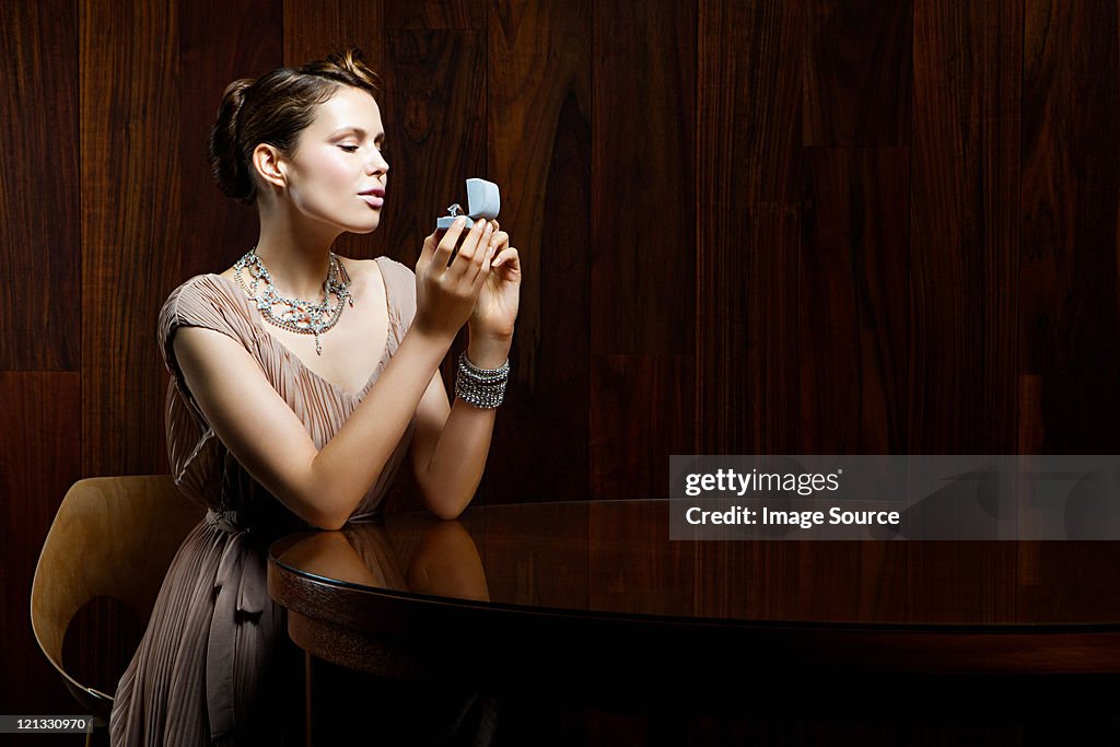 Mujer joven mirando en anillo de compromiso en caja