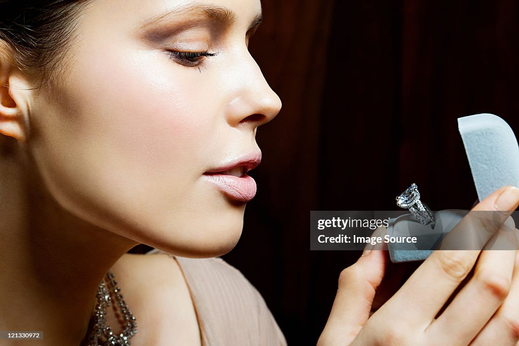 Mujer joven mirando en anillo de compromiso en caja