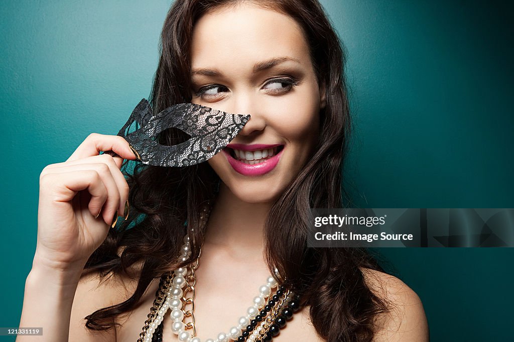 Young woman holding masquerade mask, portrait